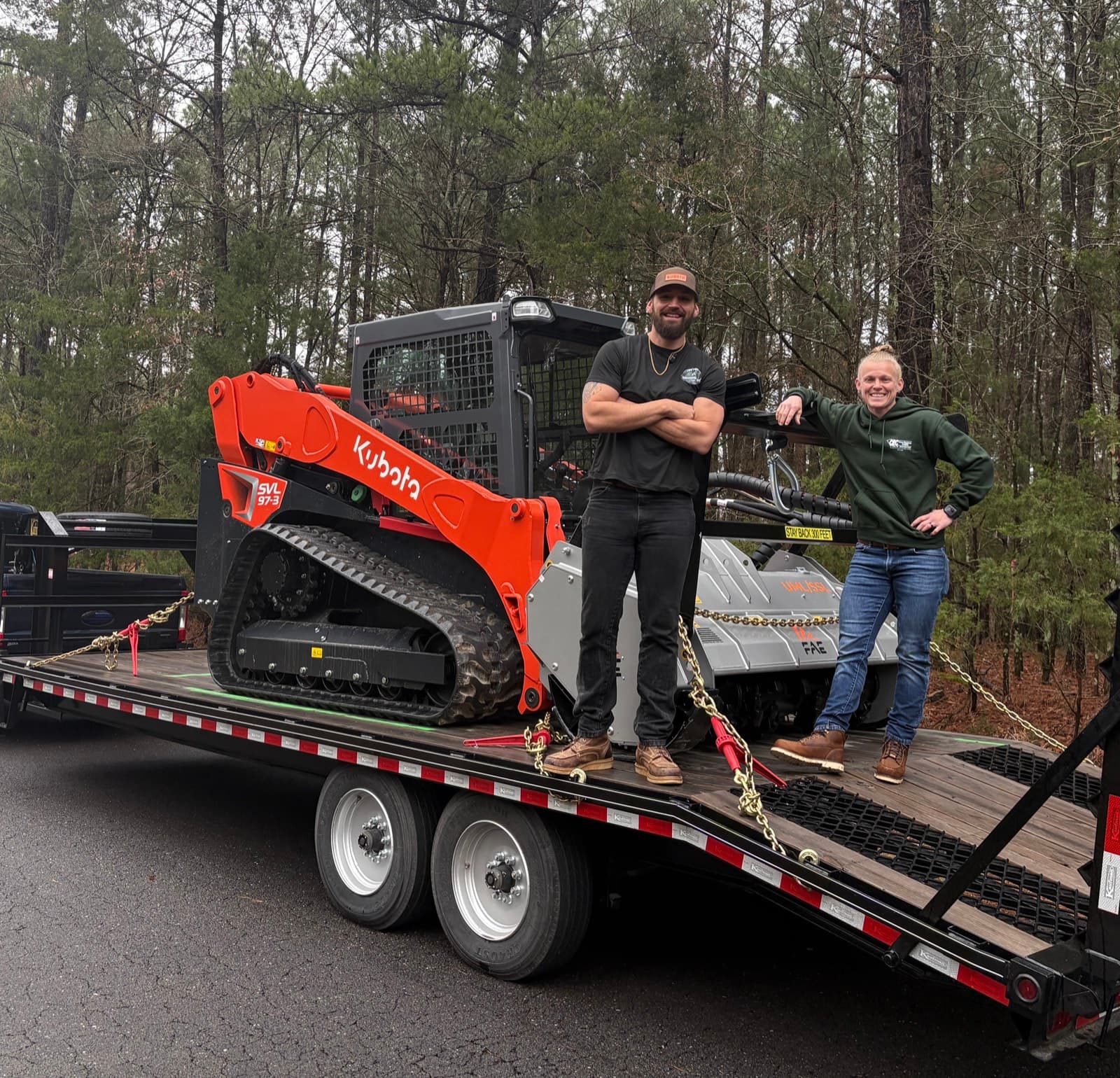 Corey and Sam — founders of A&S Brushworks — standing with their Kubota SVL 97-3 and FAE forestry mulcher
